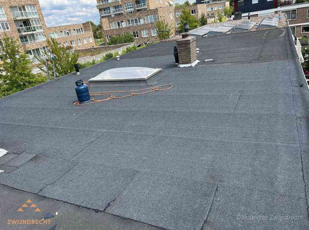 Bitumen dakbedekking op plat dak met lichtkoepel en schoorsteen in Zwijndrecht