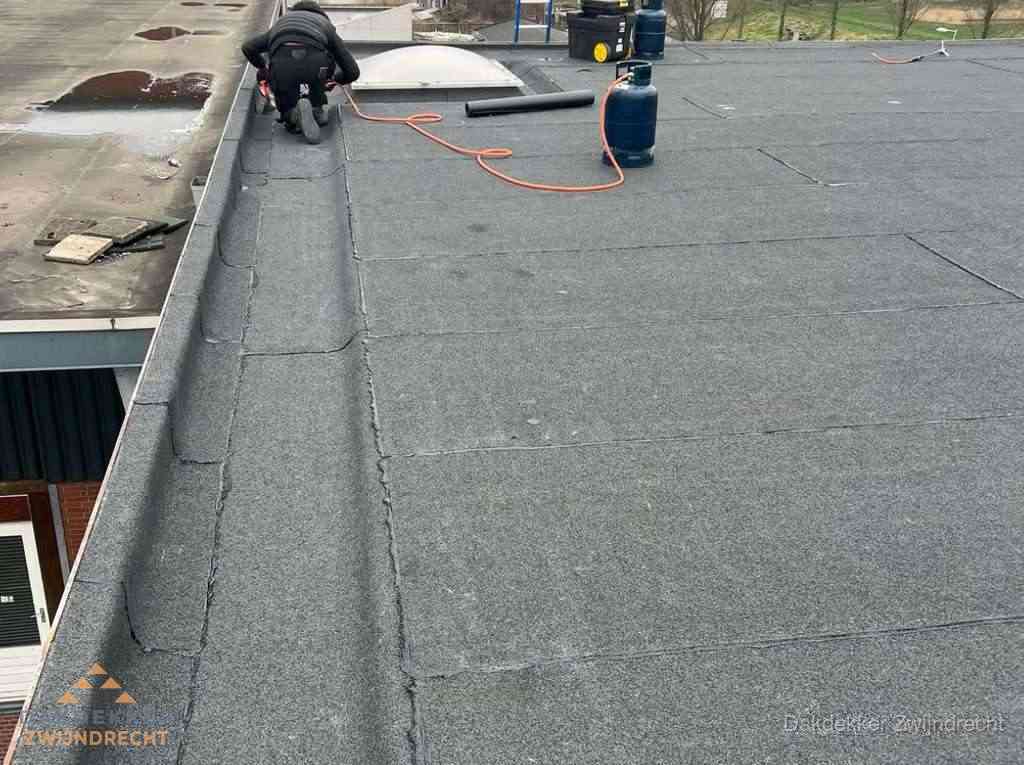 Dakdekker repareert bitumen dakbedekking op groot plat dak in Zwijndrecht